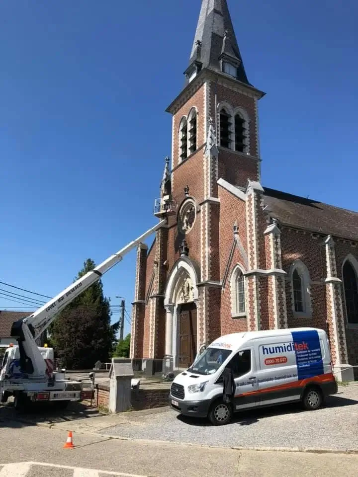 Application d’un hydrofuge sur la façade d’une église en pierre pour protéger contre l’humidité et les intempéries.