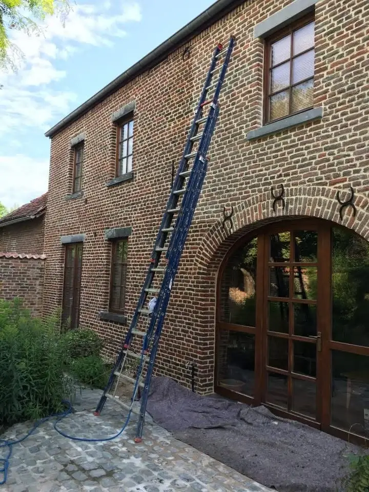 "Façade d’une maison en cours d’application d’un hydrofuge, avec pulvérisateur en action pour protéger contre l’humidité.