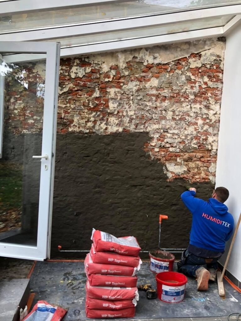 Application d’un cimentage étanche sur un mur intérieur en briques, dans le cadre d’un traitement contre l’humidité.