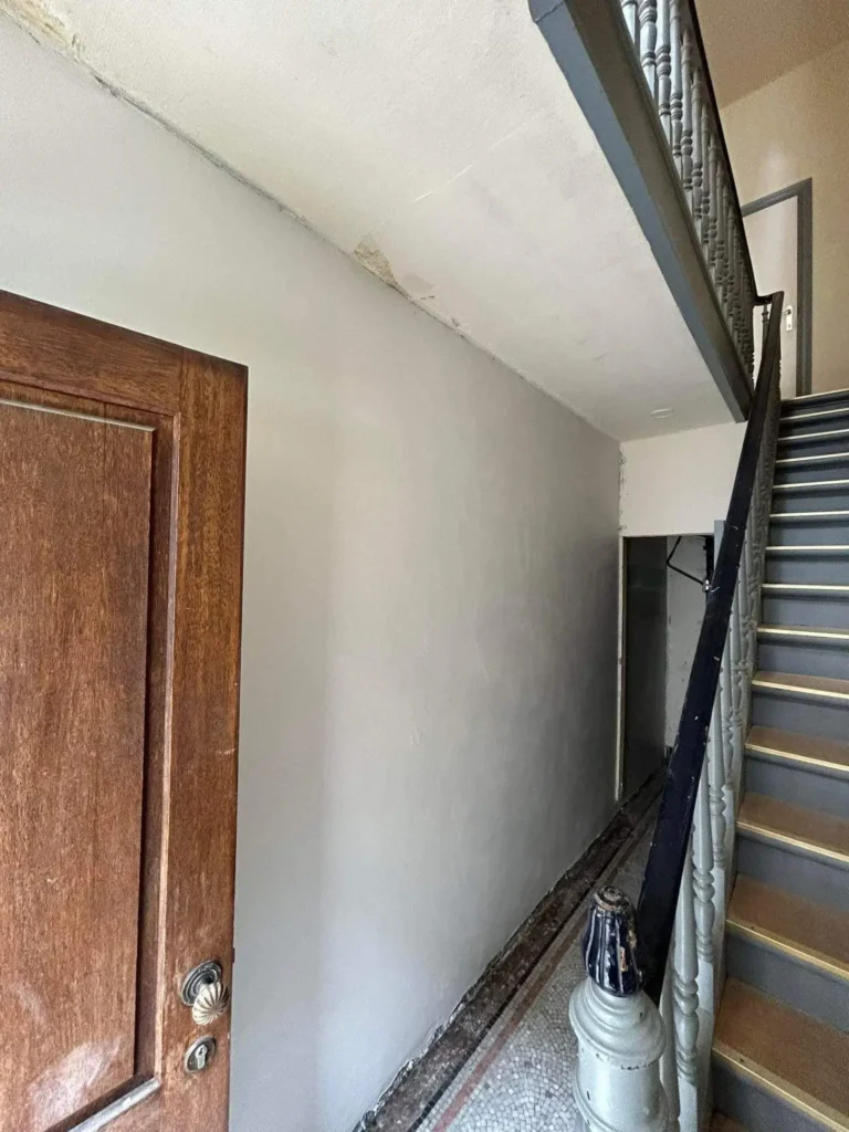 Mur intérieur fortement dégradé par l’humidité, avec enduit cloqué et peinture écaillée avant intervention de traitement.