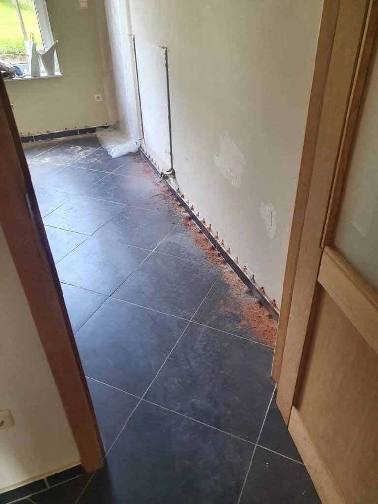 Ouvrier effectuant une injection dans un mur pour traitement contre l’humidité, utilisant un pistolet spécifique.