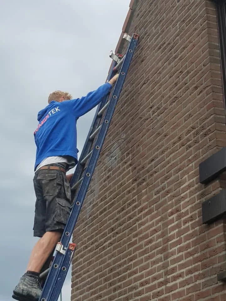 Professionnel appliquant un hydrofuge de façade avec pulvérisateur – traitement contre l’humidité des murs extérieurs
